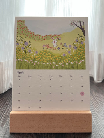 Calendar with the cat, bunny, hamster and pigeon play at a flower garden, placed on the wooden stand. The flower garden represents the arrical of spring in March