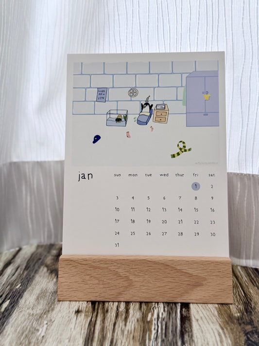 Hand drawn January calendar featuring a penguin waking up on a New Year’s Day, with a wooden stand