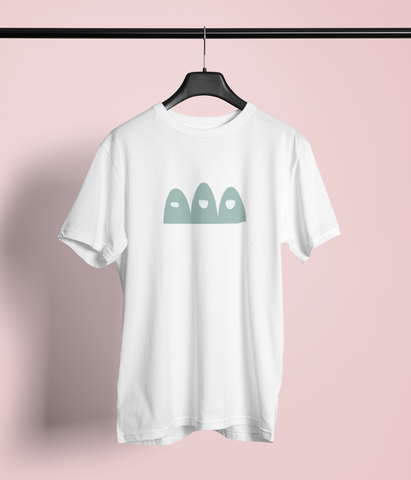 White T-shirt with a graphic design on the front. The design features three stylized, teal-colored mountains drawn by a child, each with a white cloud near the top, giving them a minimalist and abstract appearance. The T-shirt is displayed on a hanger against a plain background