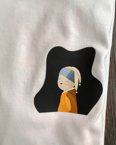 Close up of the illustration on a white t-shirt. The design is a whimsical twist on Johannes Vermeer's 'Girl with a Pearl Earring', featuring a bunny wearing pearl earrings. The image is cute and subtle